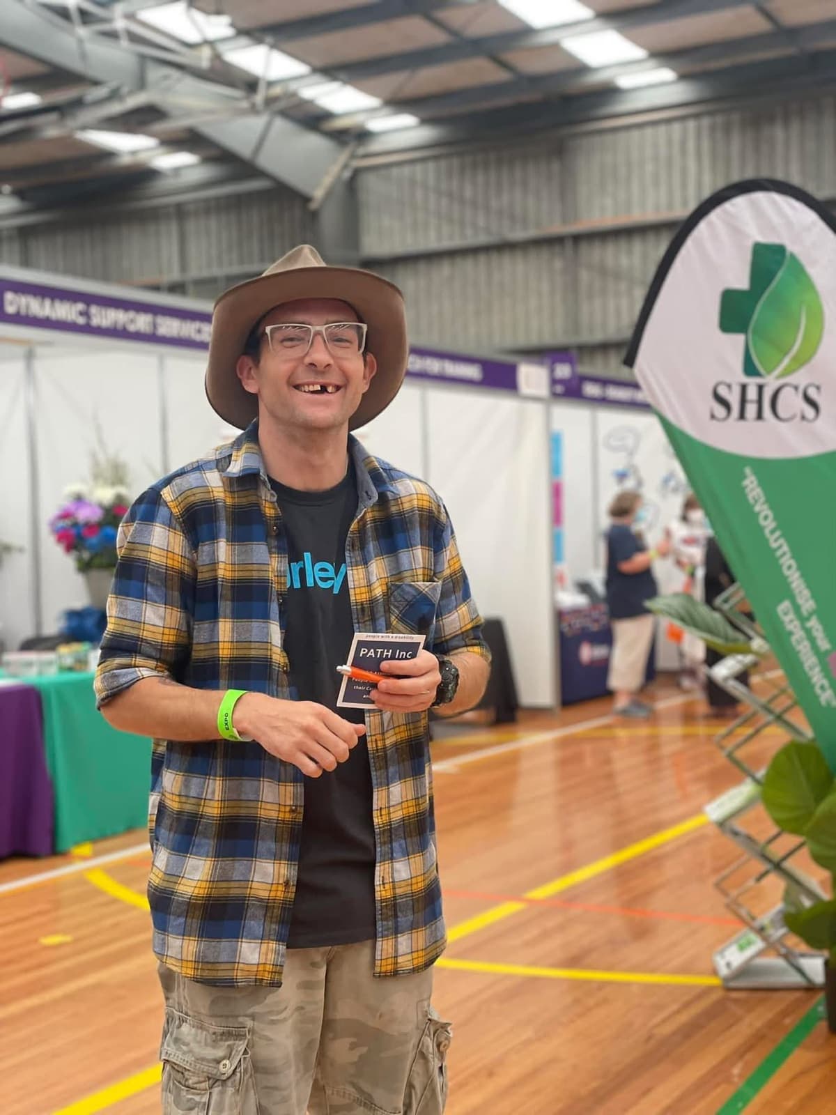 A participant in a wide-brim hat smiling at a disability services expo.